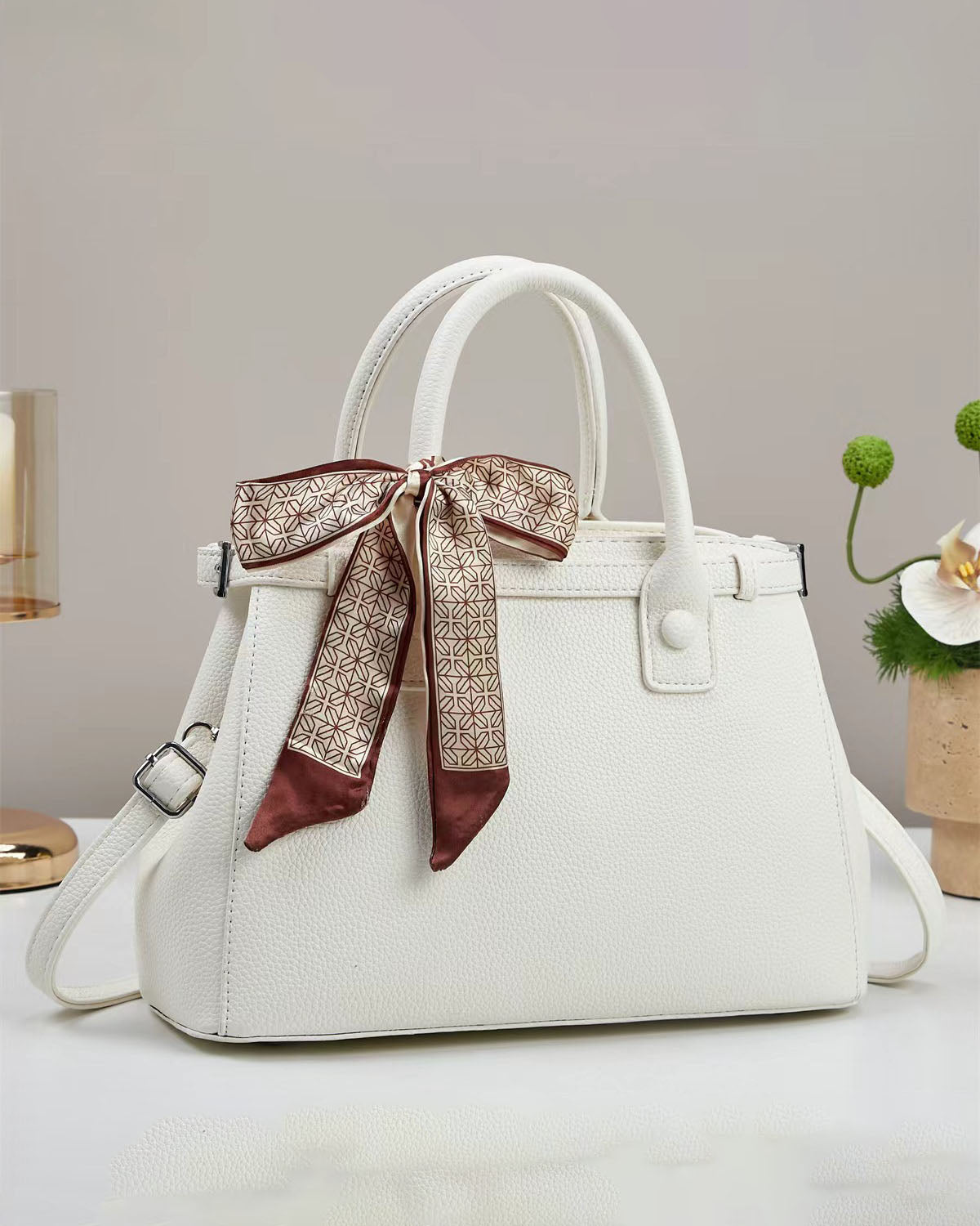 Bolso de mano con textura y un pañuelo de seda atado al asa