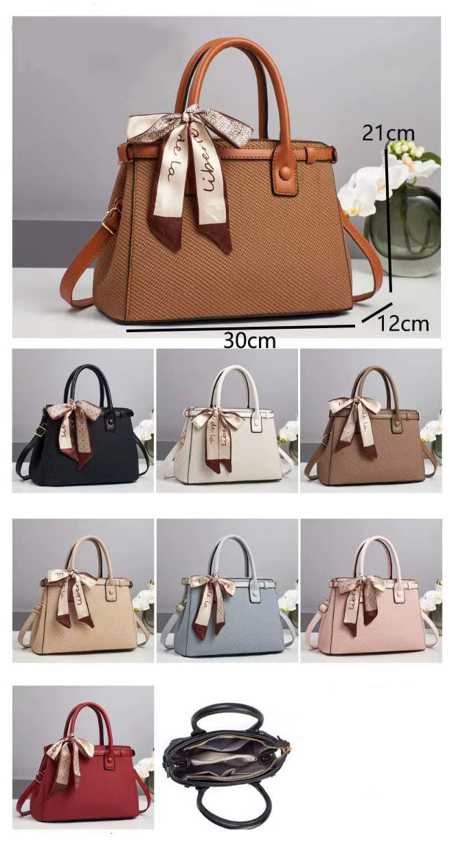 Bolso de mano con textura y un pañuelo de seda atado al asa.
