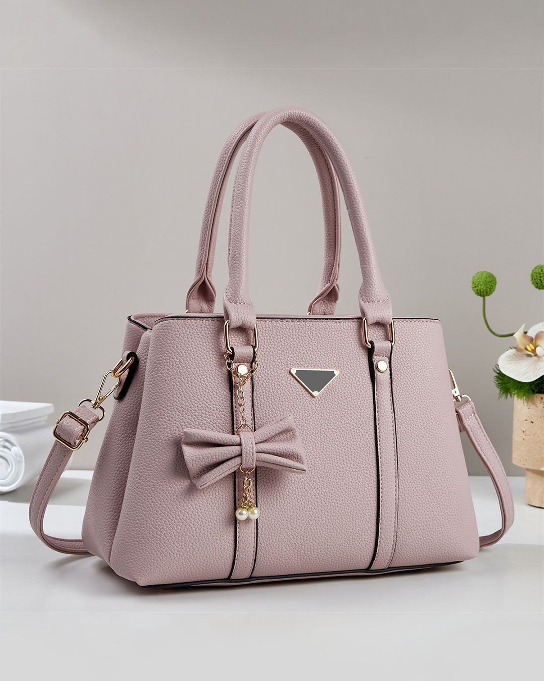 Cartera mediana con colgante de lazo y detalles en dorado
