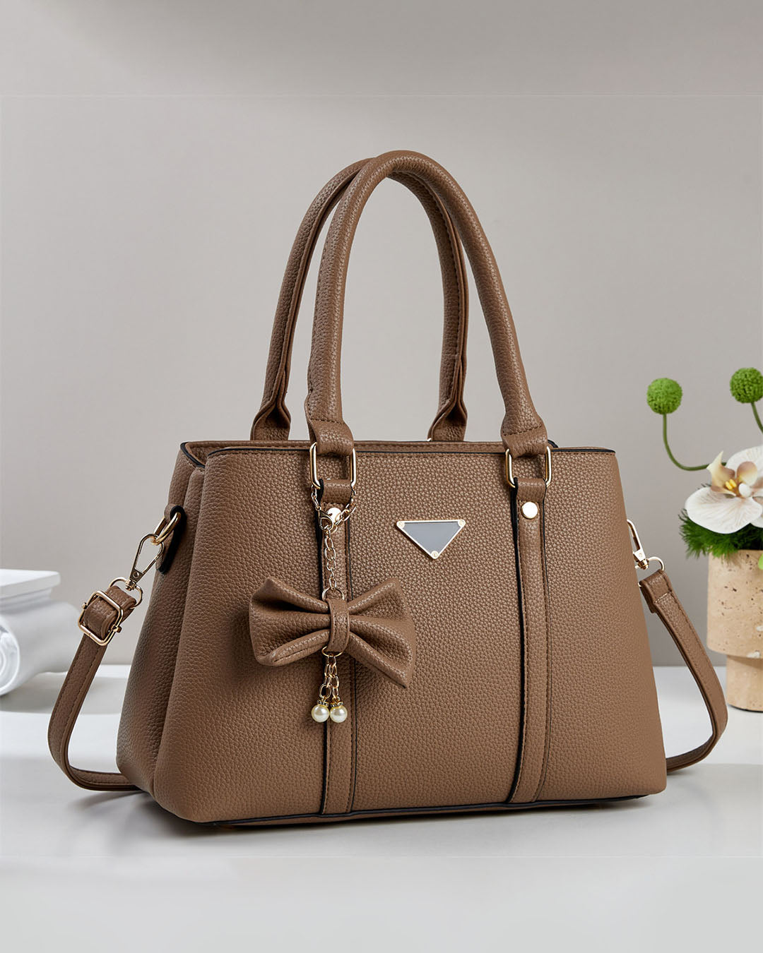 Cartera mediana con colgante de lazo y detalles en dorado