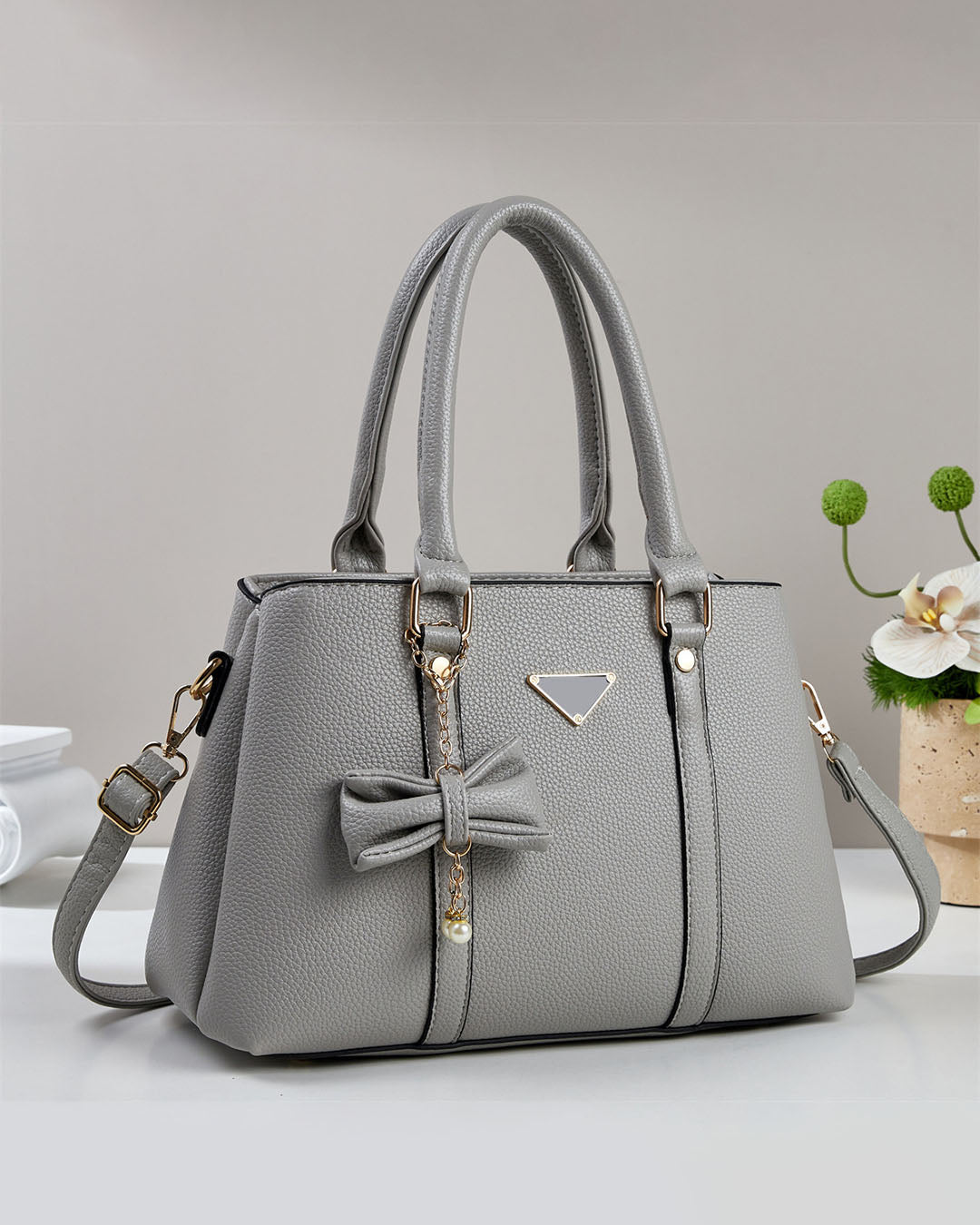 Cartera mediana con colgante de lazo y detalles en dorado