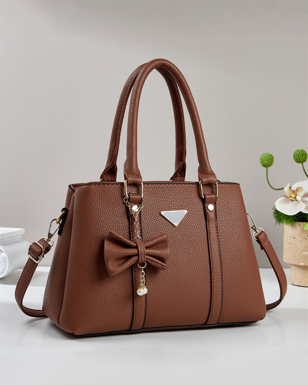 Cartera mediana con colgante de lazo y detalles en dorado