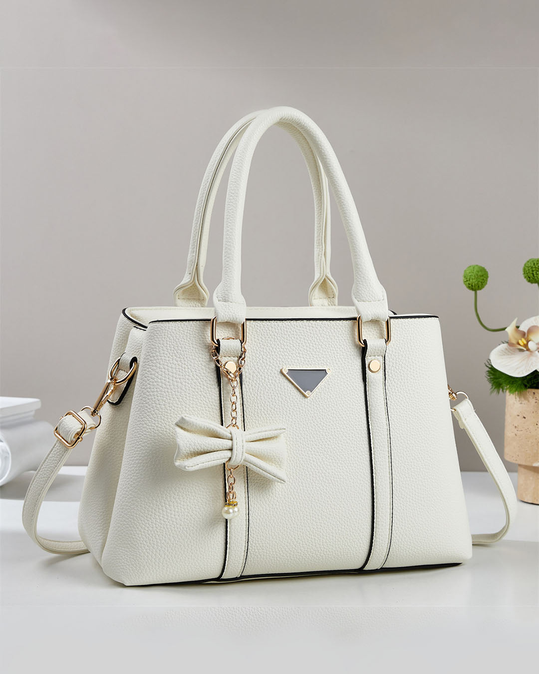 Cartera mediana con colgante de lazo y detalles en dorado