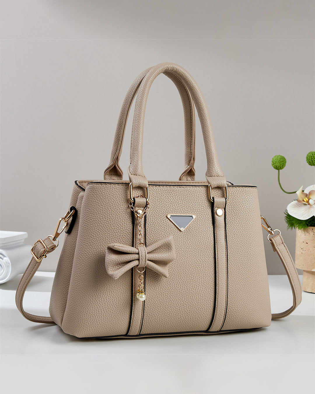 Cartera mediana con colgante de lazo y detalles en dorado
