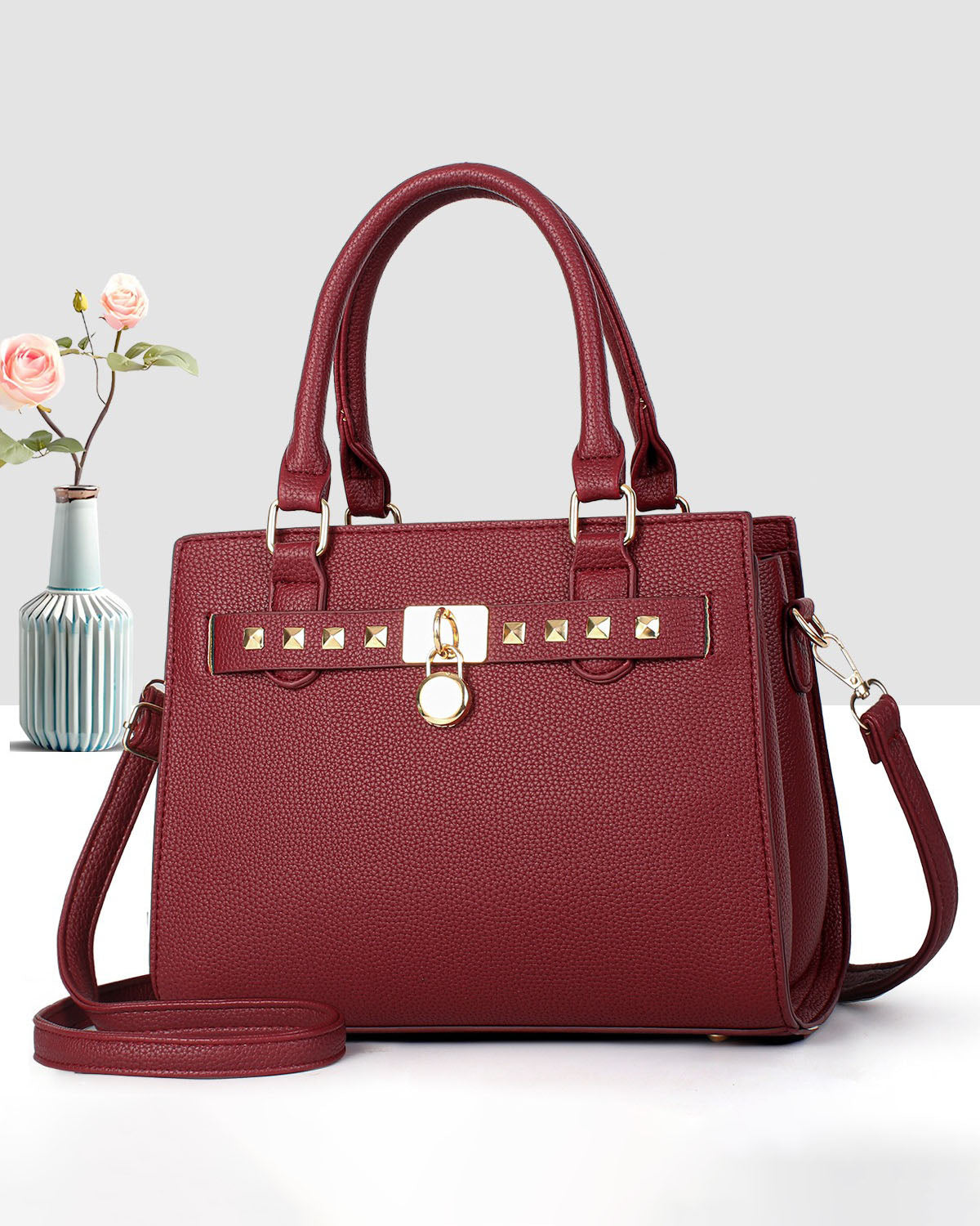Cartera mediana de mano con detalles y tachuelas frontales en dorado