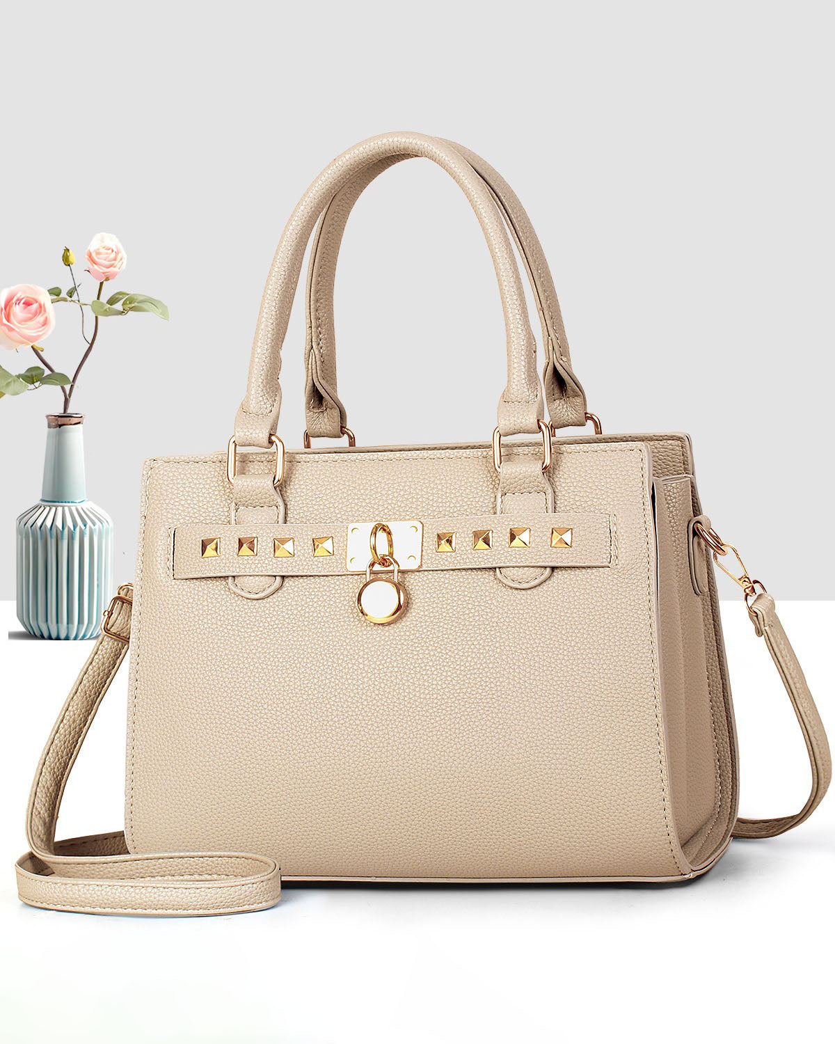 Cartera mediana de mano con detalles y tachuelas frontales en dorado