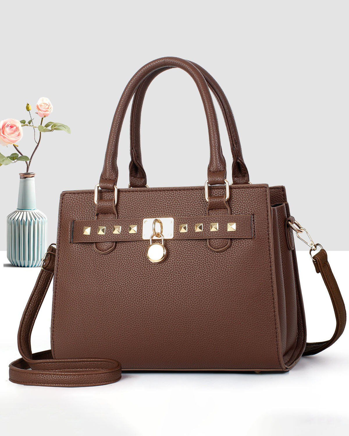 Cartera mediana de mano con detalles y tachuelas frontales en dorado