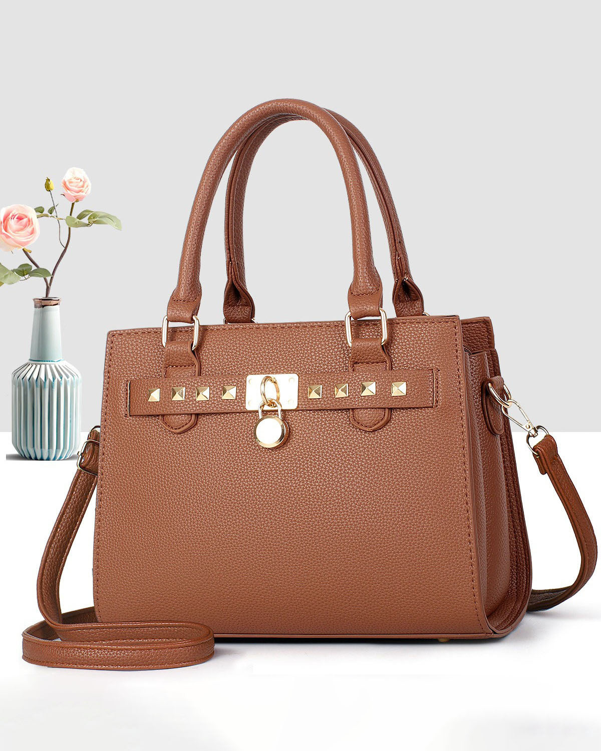 Cartera mediana de mano con detalles y tachuelas frontales en dorado