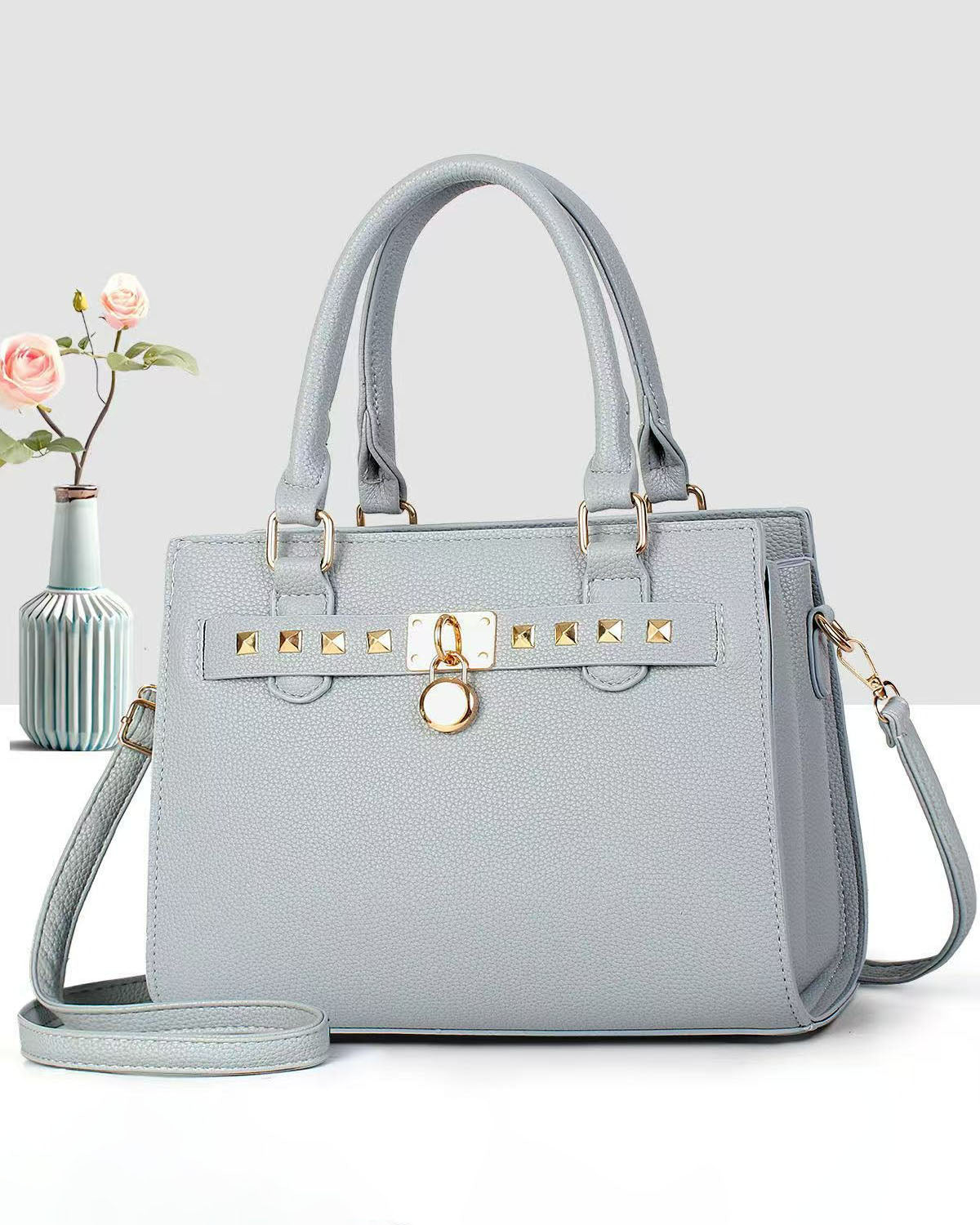 Cartera mediana de mano con detalles y tachuelas frontales en dorado