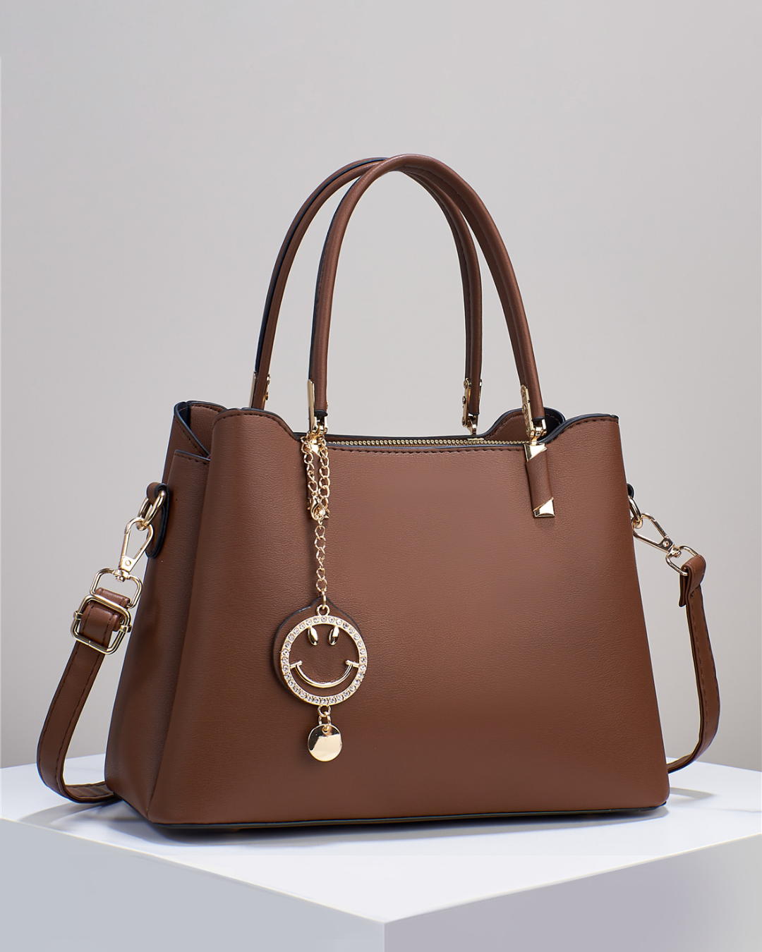 Bolso de mano con colgante sonriente. Detalles en dorado. Tiro para hombro