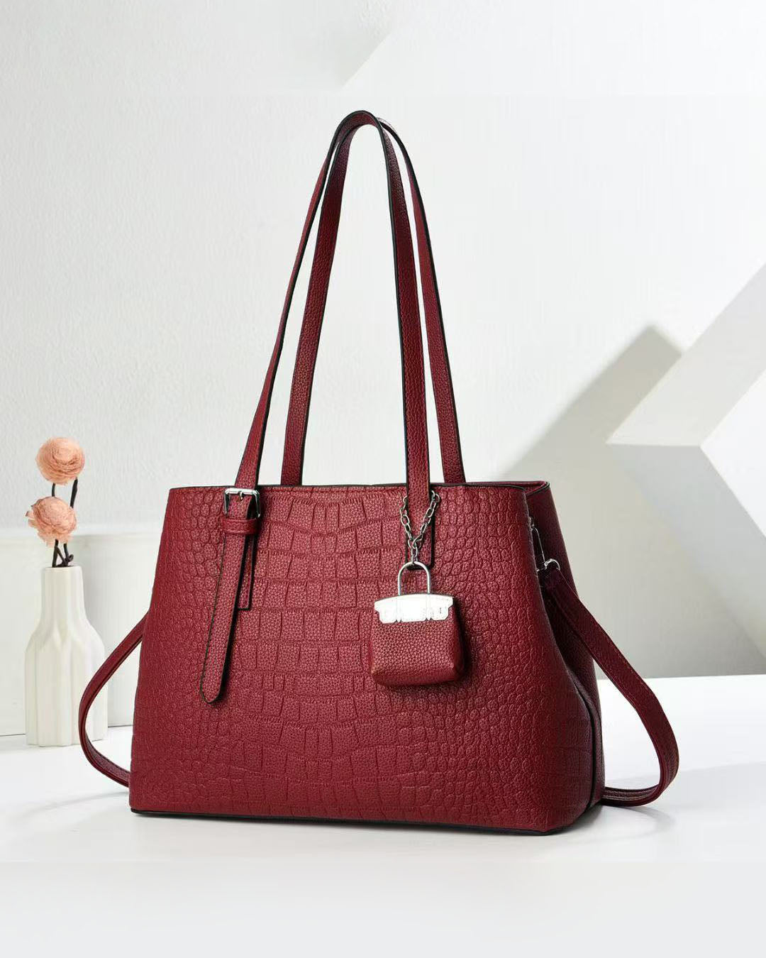 Cartera espaciosa con llavero colgante y detalles en plateado