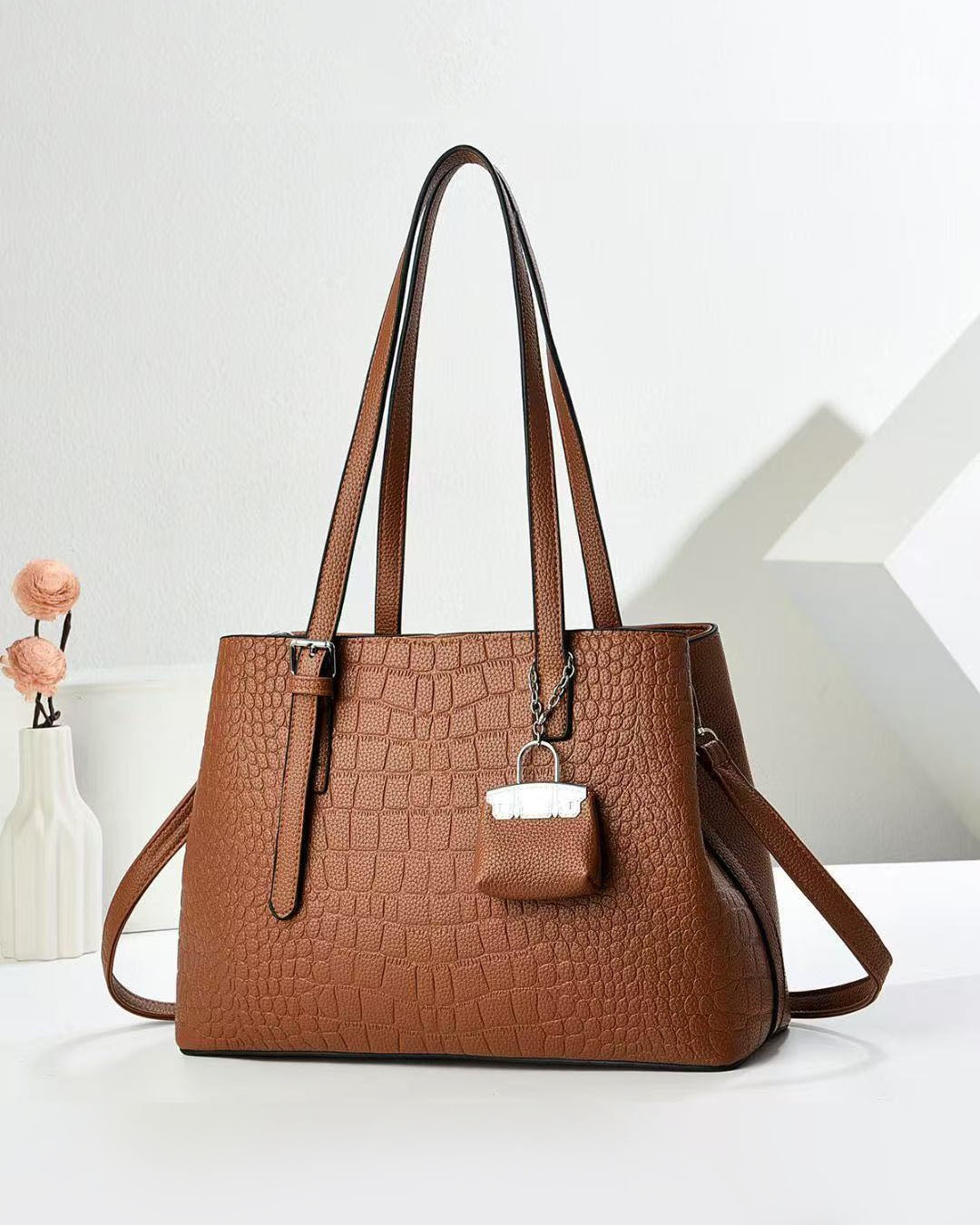 Cartera espaciosa con llavero colgante y detalles en plateado