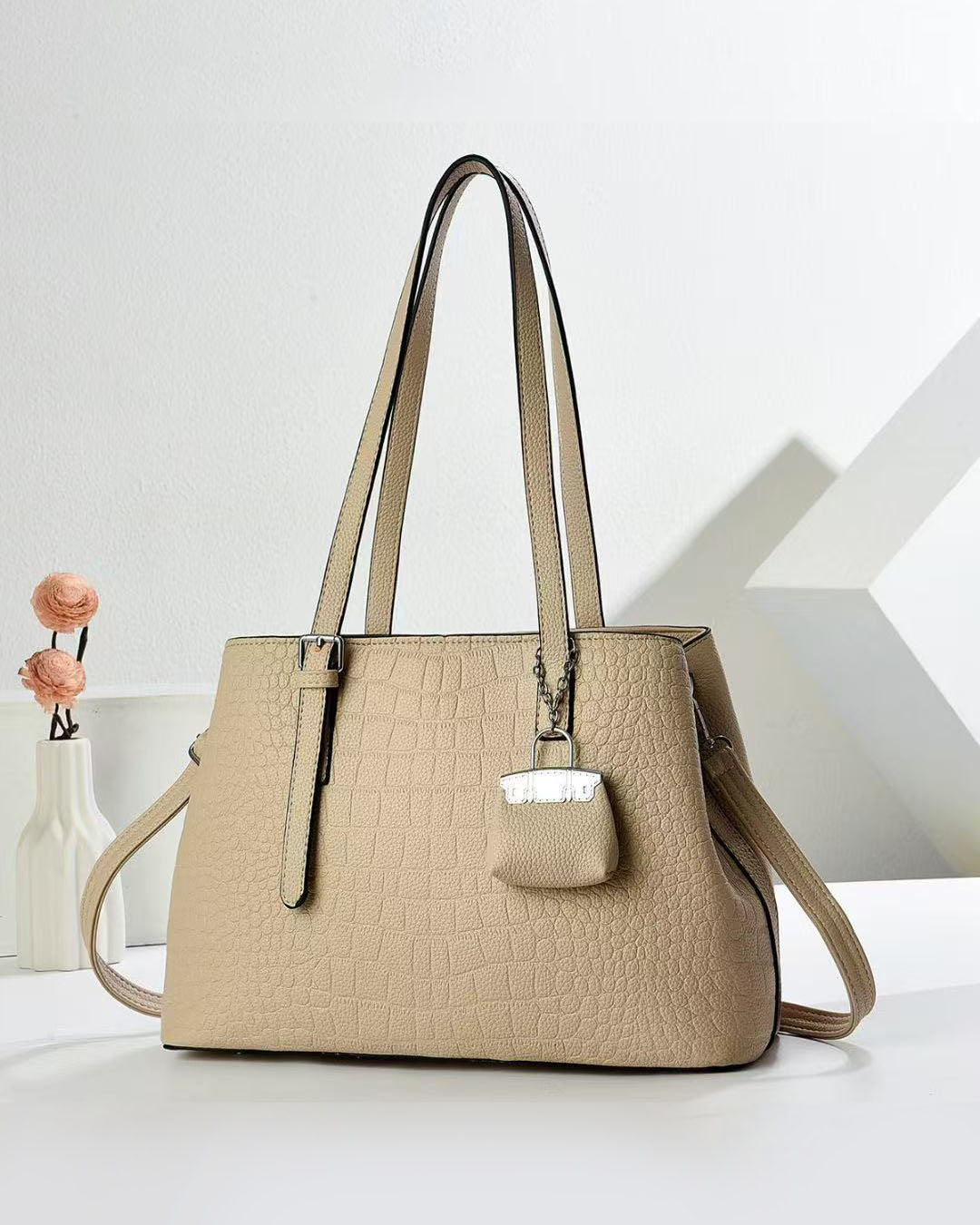 Cartera espaciosa con llavero colgante y detalles en plateado