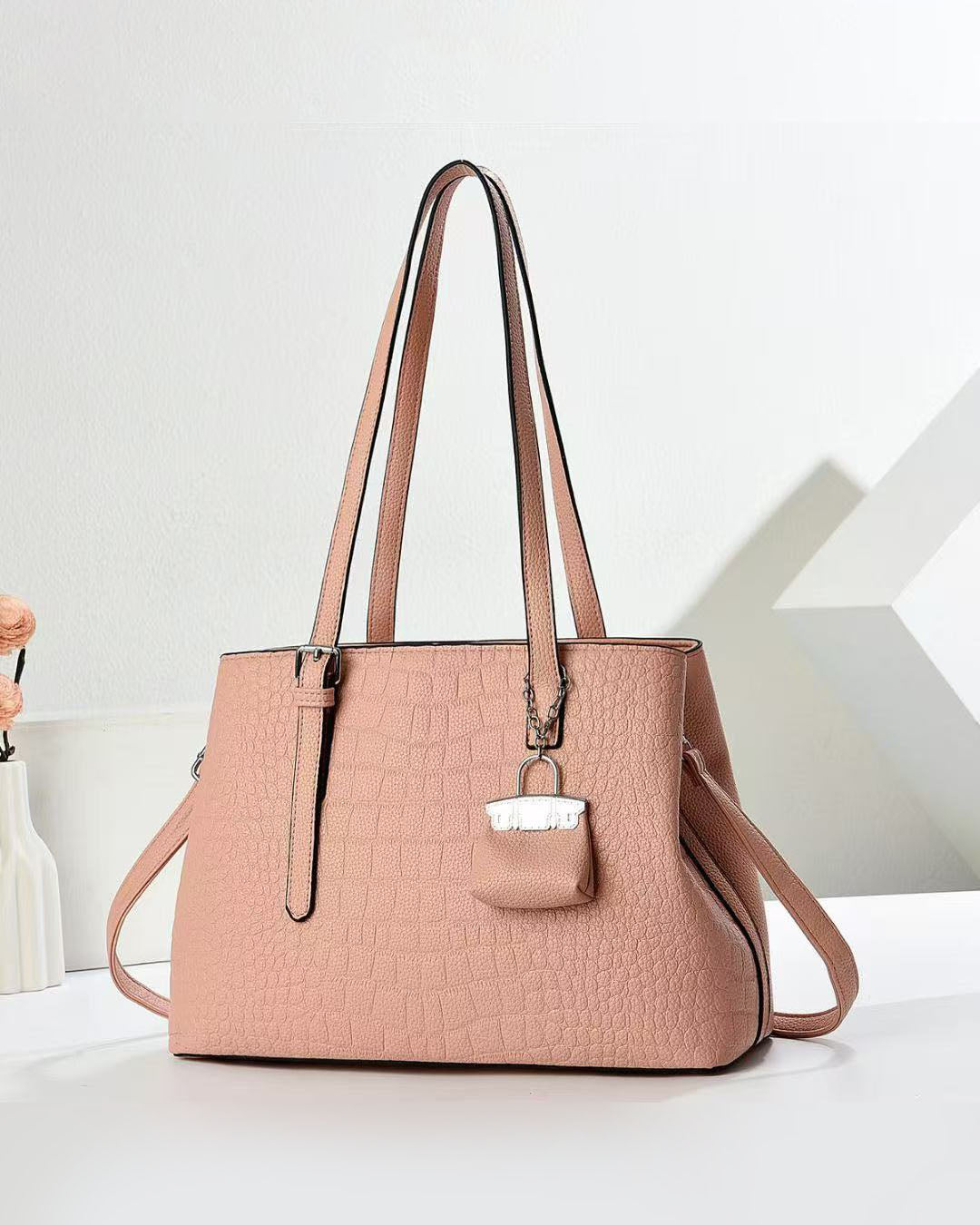 Cartera espaciosa con llavero colgante y detalles en plateado