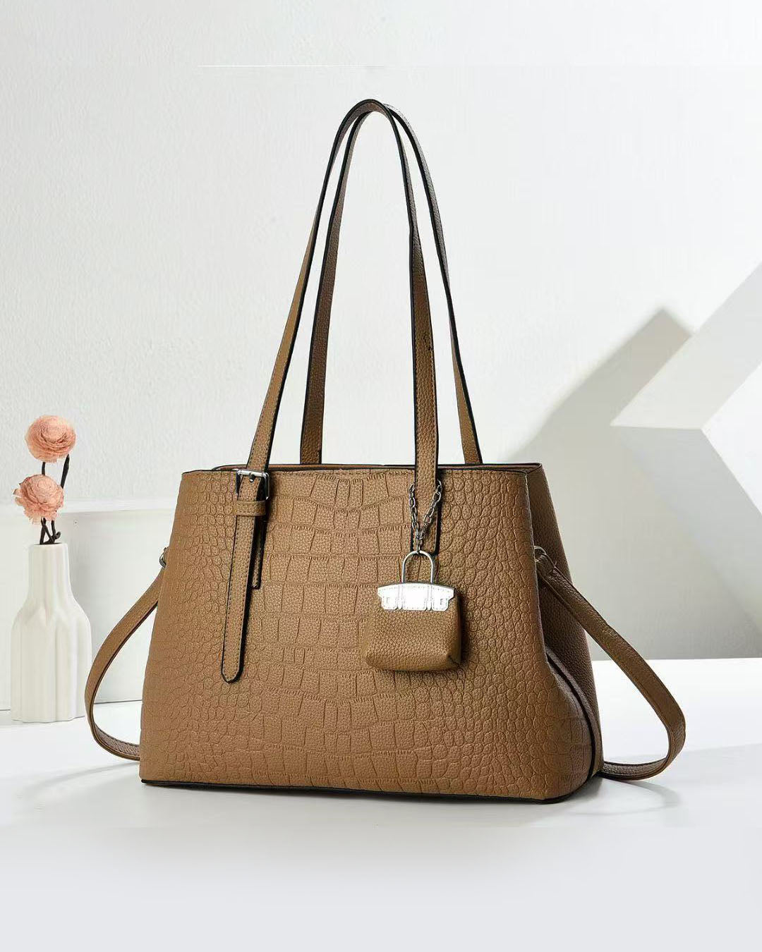 Cartera espaciosa con llavero colgante y detalles en plateado