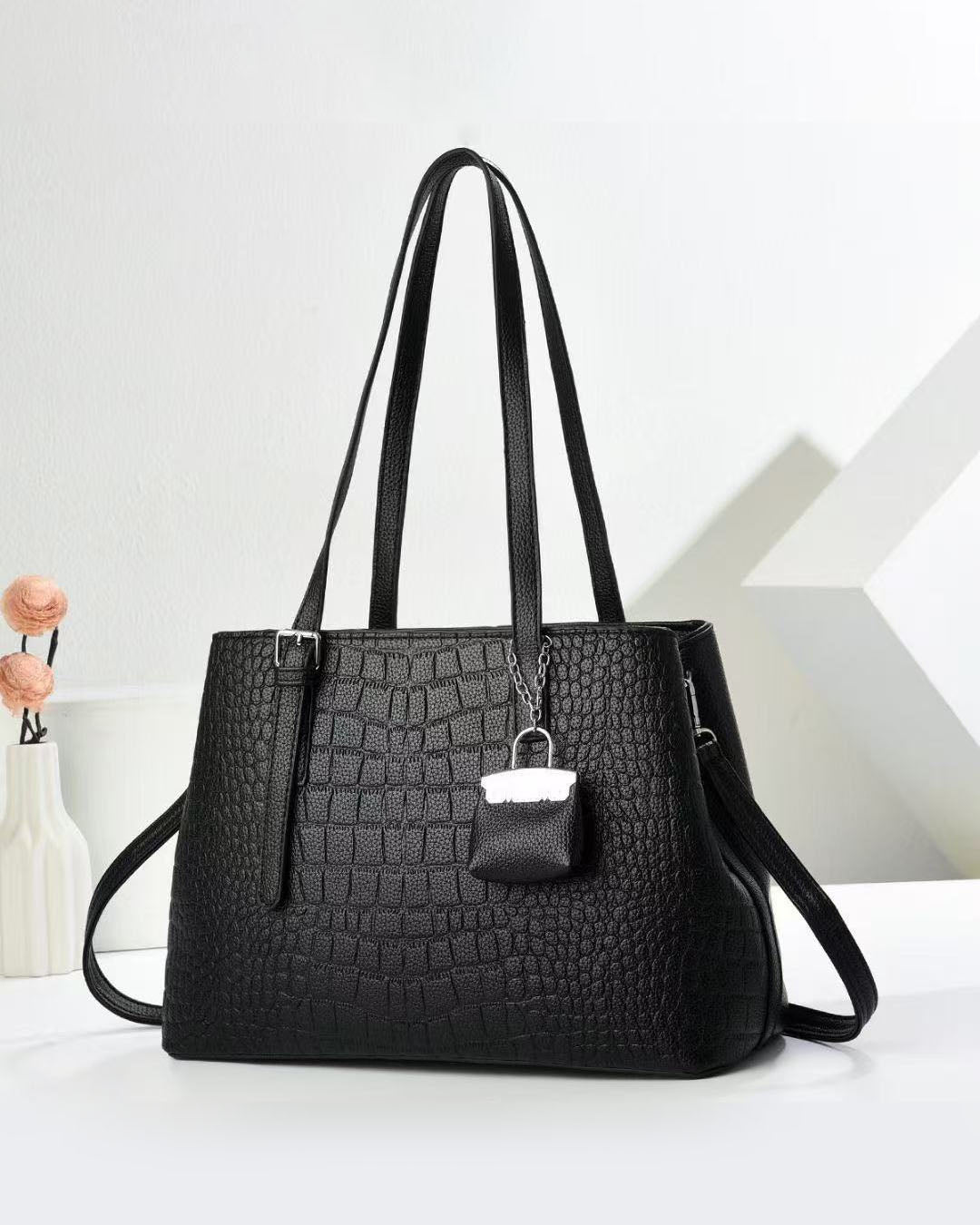 Cartera espaciosa con llavero colgante y detalles en plateado