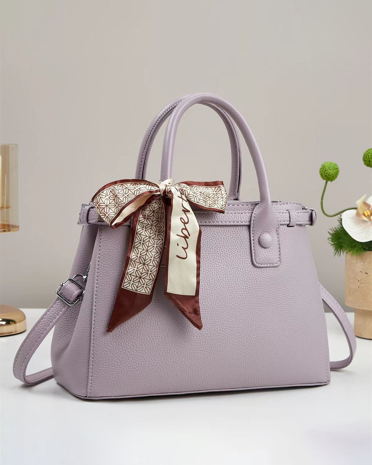 Bolso de mano con textura y un pañuelo de seda atado al asa