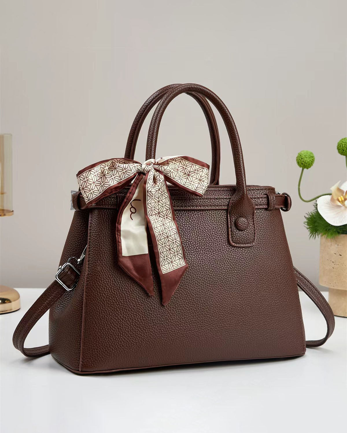 Bolso de mano con textura y un pañuelo de seda atado al asa