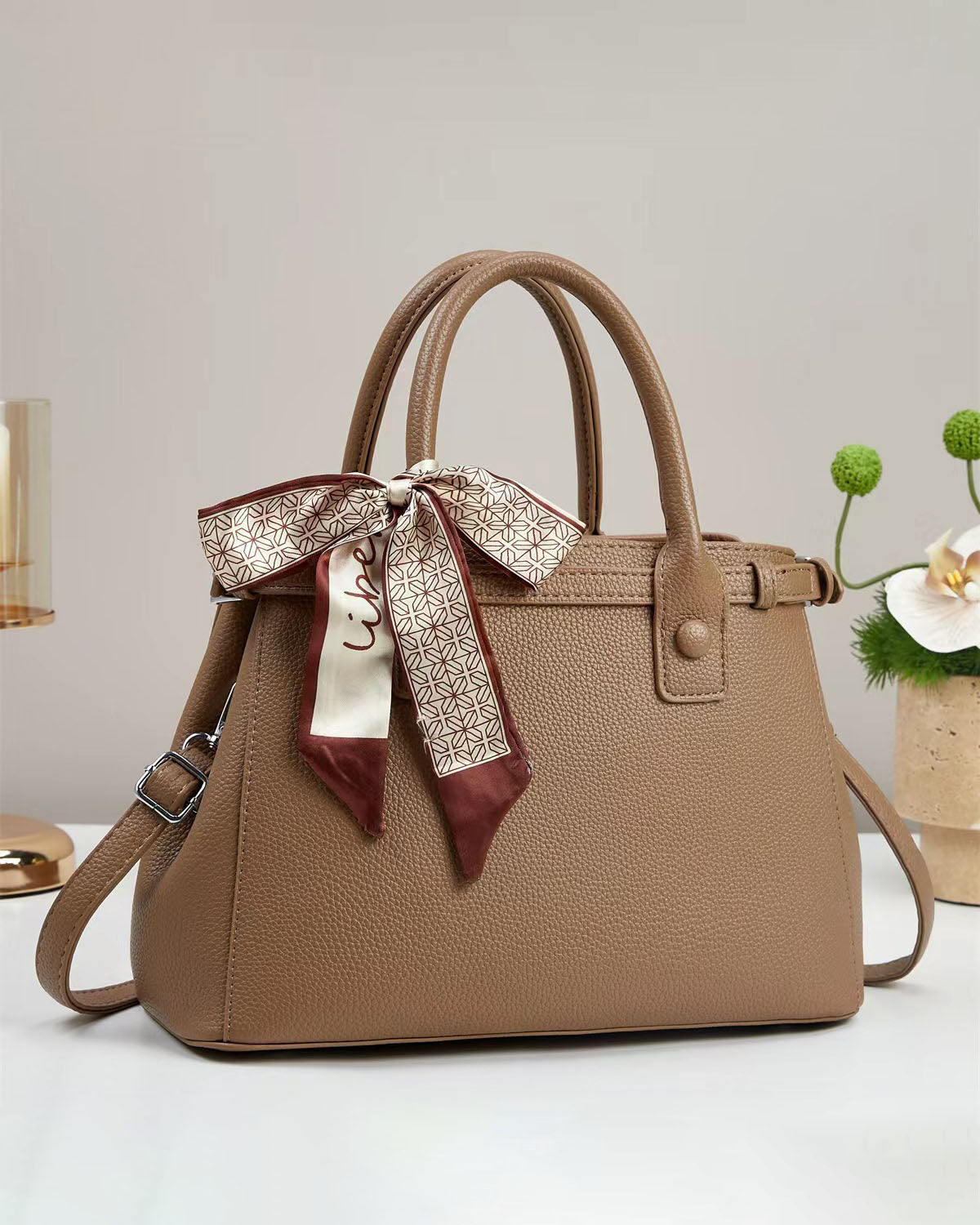 Bolso de mano con textura y un pañuelo de seda atado al asa