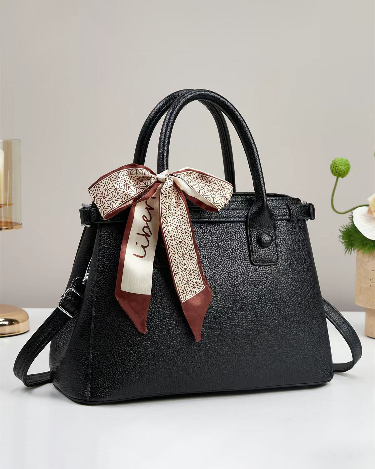 Bolso de mano con textura y un pañuelo de seda atado al asa