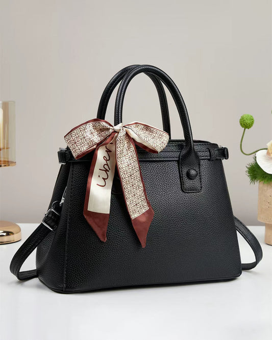 Bolso de mano con textura y un pañuelo de seda atado al asa